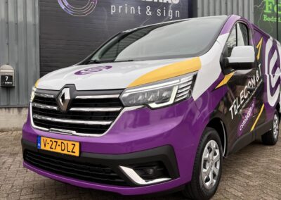 Vooraanzicht van designwrap op Renault bedrijfswagen van CS Telecom & IT, met paars-wit-geel kleurverloop en logo, gefotografeerd bij Elenbaas Print & Sign.